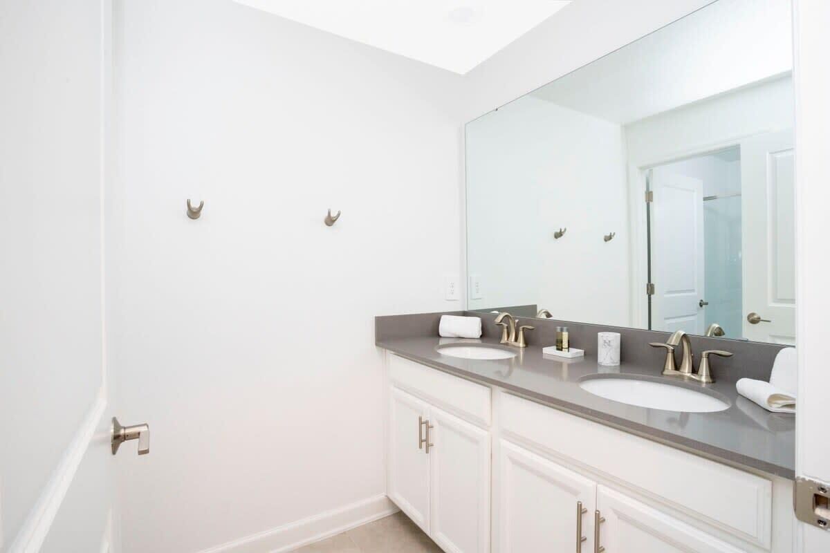 Un baño moderno con dos lavamanos, un espejo grande y una puerta con pomo.