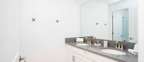 Un baño moderno con dos lavamanos, un espejo grande y una puerta con pomo.