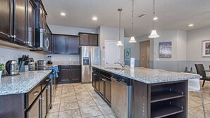 A modern kitchen with granite countertops, stainless steel appliances, and a central island. - Home 8 Bdrm at Windsor Westside With Top Amenities (Kissimmee)