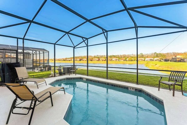 A swimming pool with lounge chairs and a view of a lake and distant buildings. - Lake View and Private Pool 4BR at Bella Vida (Kissimmee)