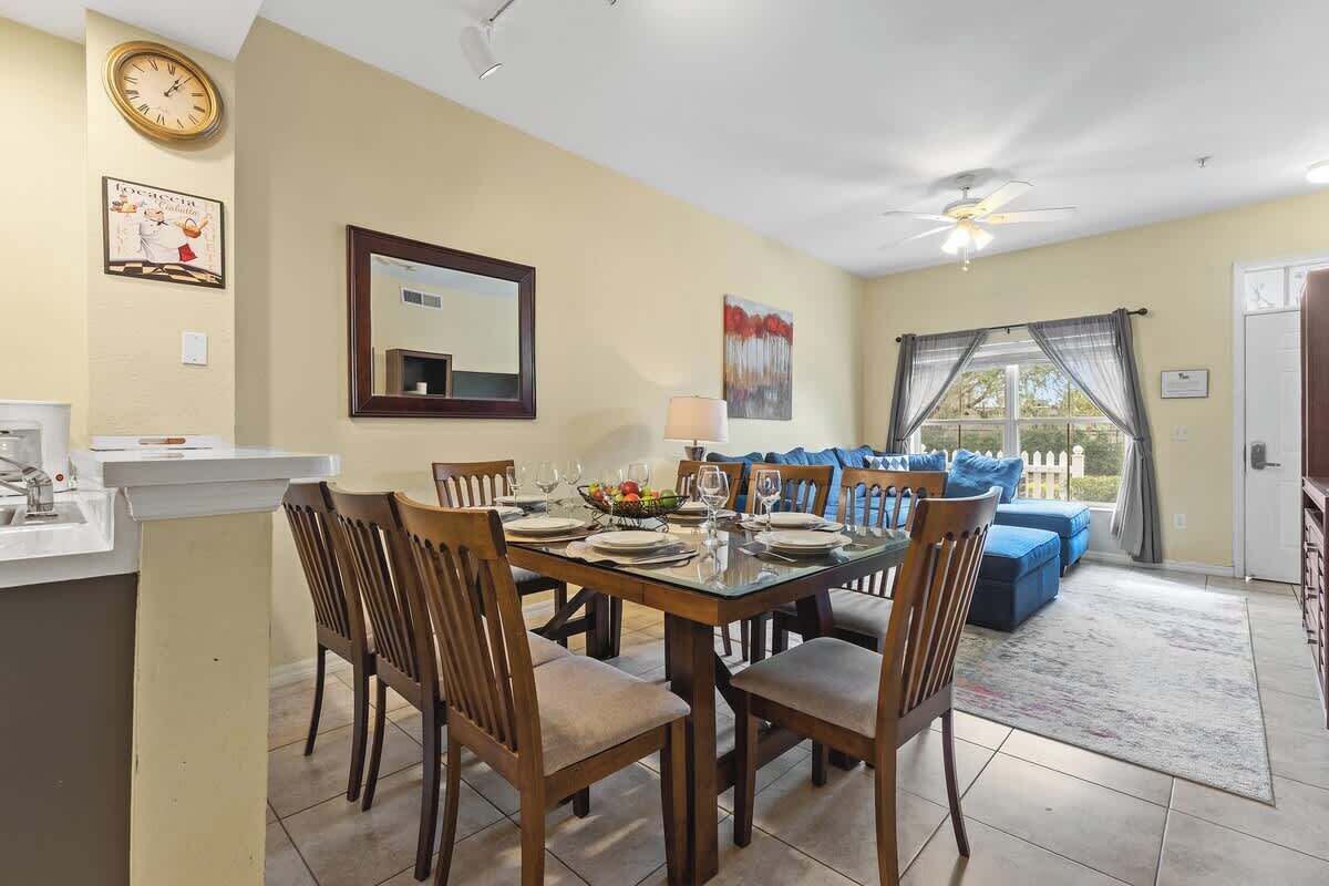 A dining area with a table set for four, surrounded by wooden chairs. A mirror hangs on the wall above the table.