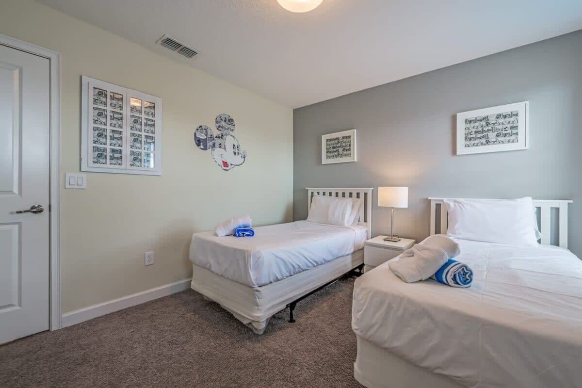 A hotel room with two beds, a white door, and wall art.