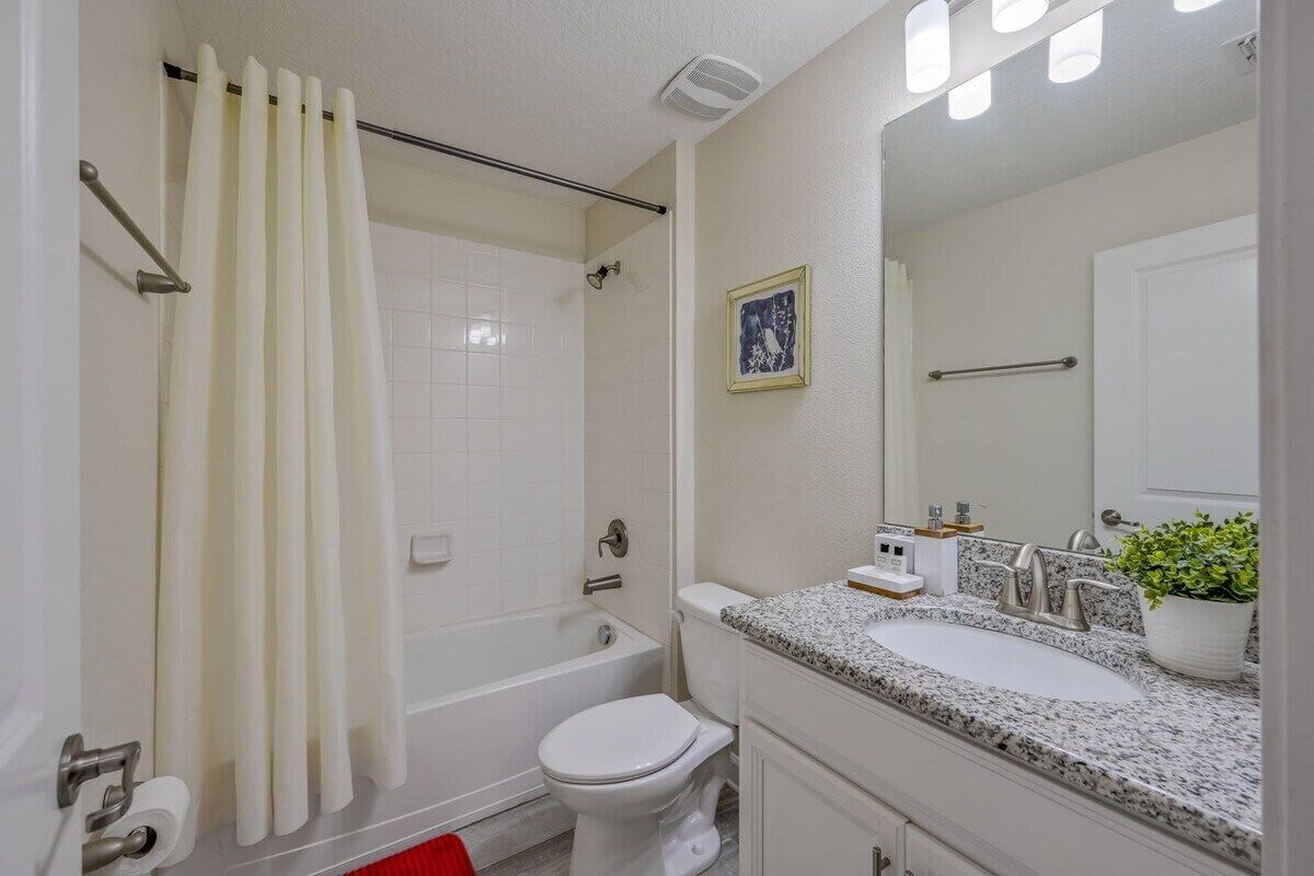 Un baño con bañera, inodoro, lavamanos y cortina de ducha.