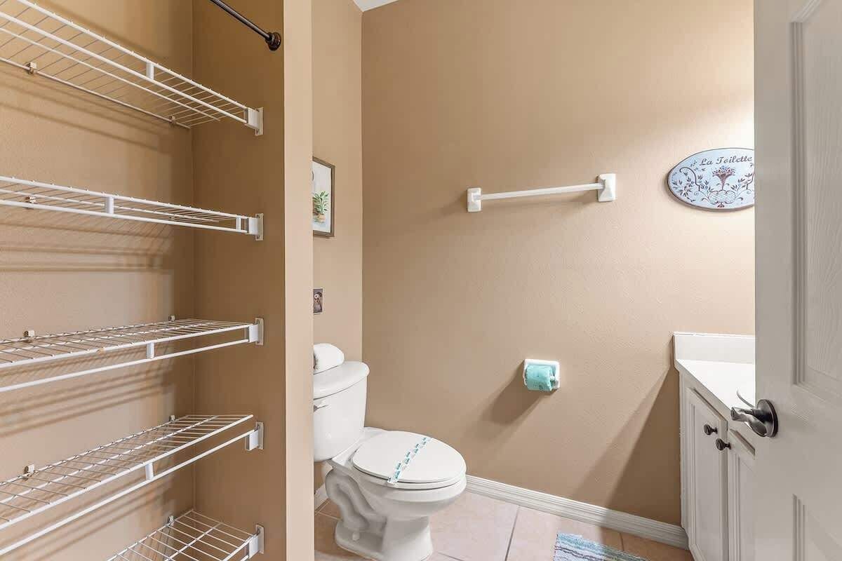 Un baño con inodoro, toallero y estante.