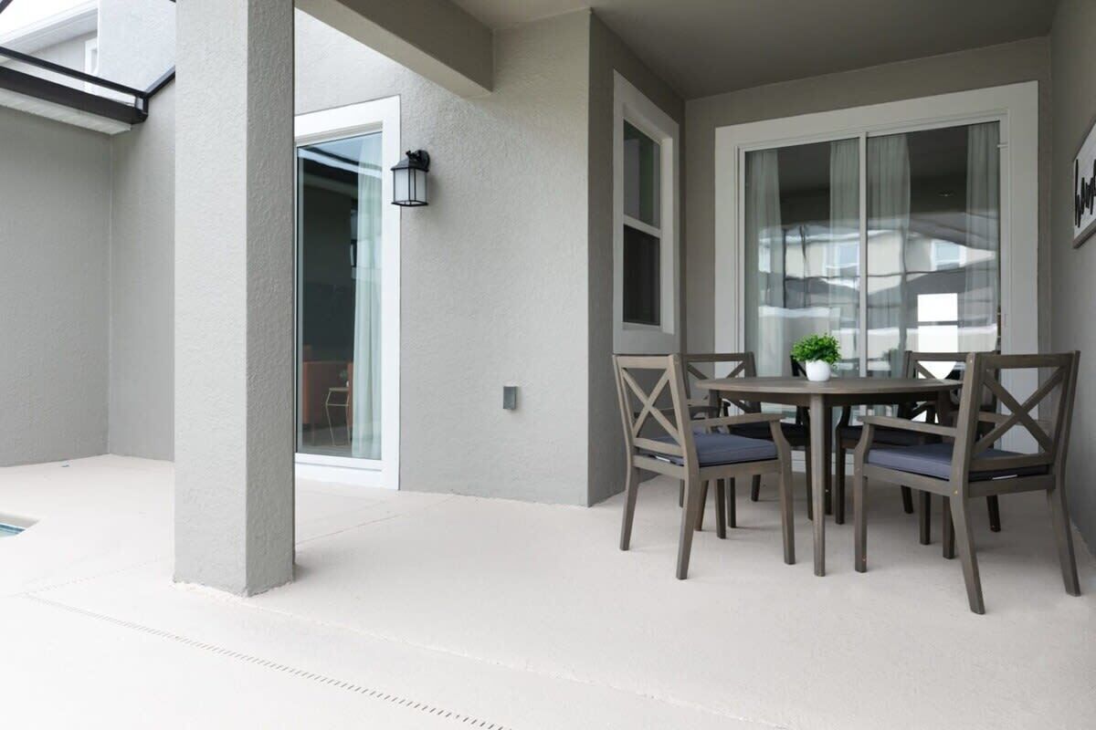 A patio area with a table and chairs, a potted plant, and a view of the outside.