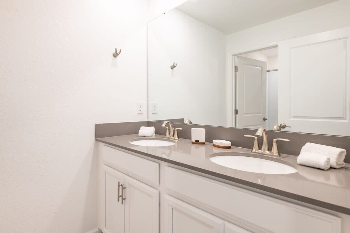 A bathroom with two sinks, a large mirror, and a door.