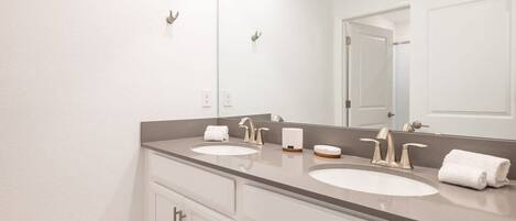A bathroom with two sinks, a large mirror, and a door.