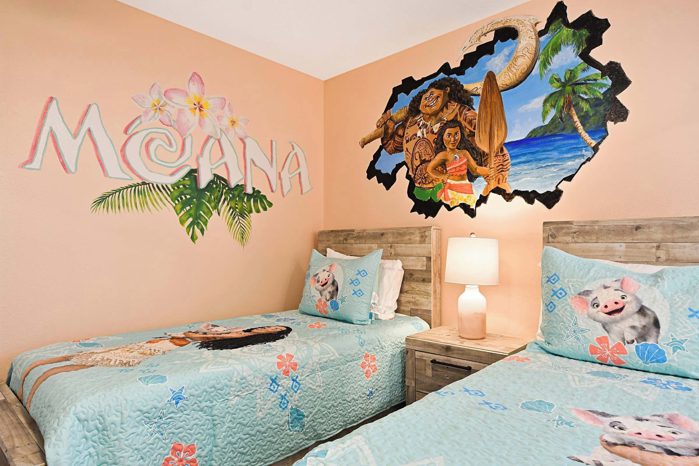 A room with two beds, a wall mural, and a tropical-themed pillow.