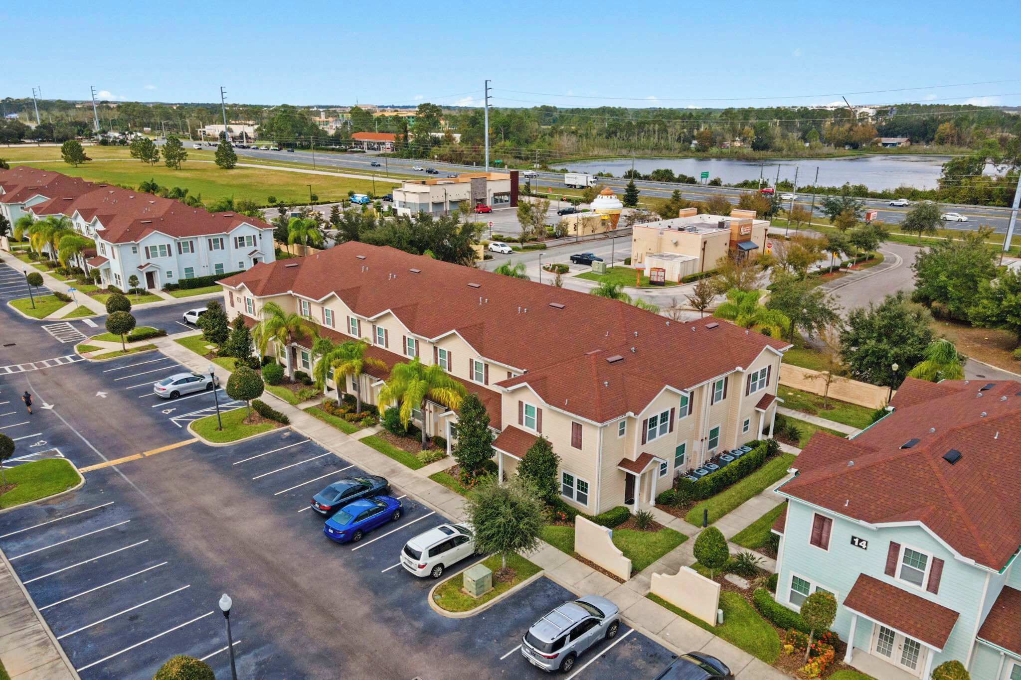 Un quartier résidentiel composé de maisons de ville, d’un parking et, au loin, d’une étendue d’eau.