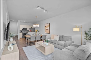 Un salon moderne avec un canapé gris, une table basse en bois et un coin repas comprenant une table et des chaises.