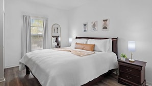 Un dormitorio con cama, mesitas de noche, lámpara y decoración en la pared.