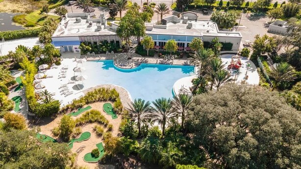 Ein Luftbild eines Resorts mit großem Schwimmbad, Golfplatz und üppiger Bepflanzung.