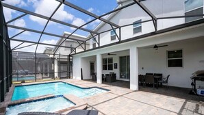 A covered outdoor pool area with lounge chairs, a hot tub, and a patio with tables and chairs. - Modern Marvel-spacious, Themed, Fun-filled (Kissimmee)