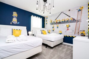 A hotel room with two beds, a desk, and a wall decorated with minion characters. - Modern Marvel-spacious, Themed, Fun-filled (Kissimmee)
