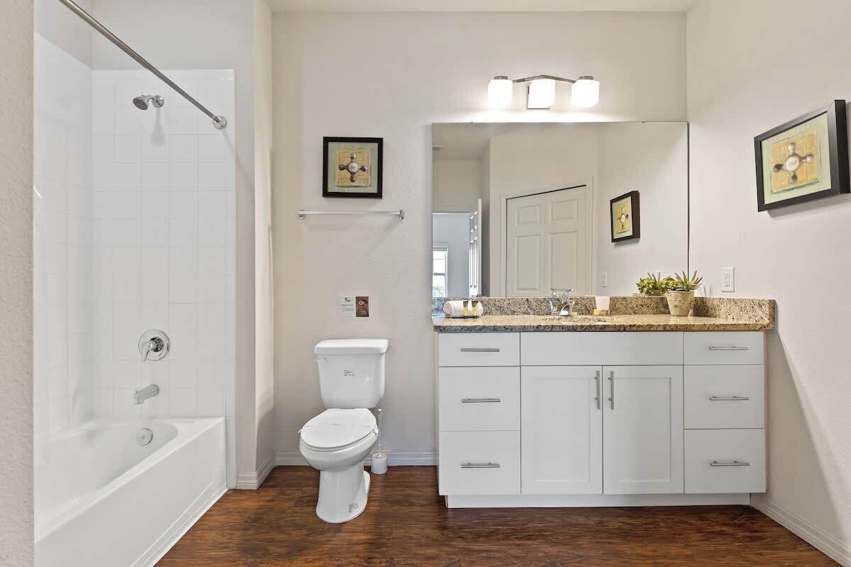 Een badkamer met een badkuip, toilet, wastafel met kastjes en een douchehoek.