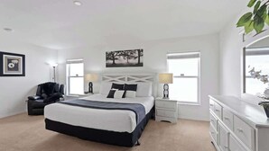 Ein Schlafzimmer mit einem Bett, Nachttischen, einem Schminktisch und einem Sessel.