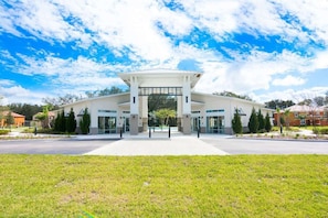 A modern building with a central entrance, surrounded by a well-maintained lawn and trees. - Game Room Plus Private Pool 4BR Disney Area (Kissimmee)