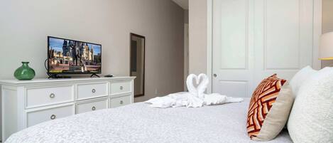 Ett hotellrum med en säng, en byrå, en tv och en dörr.