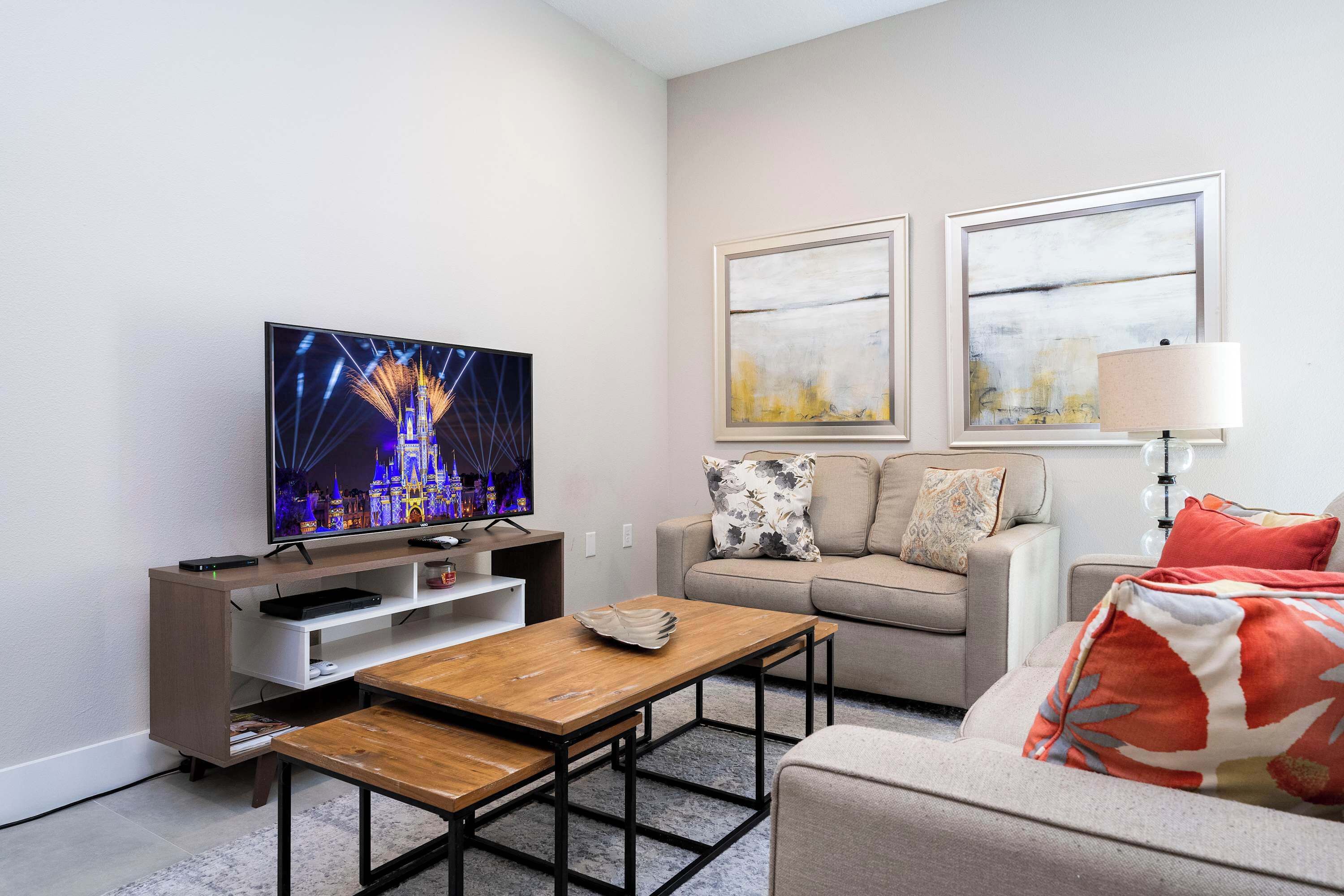 A living room with a TV, sofa, coffee table, and artwork on the wall.
