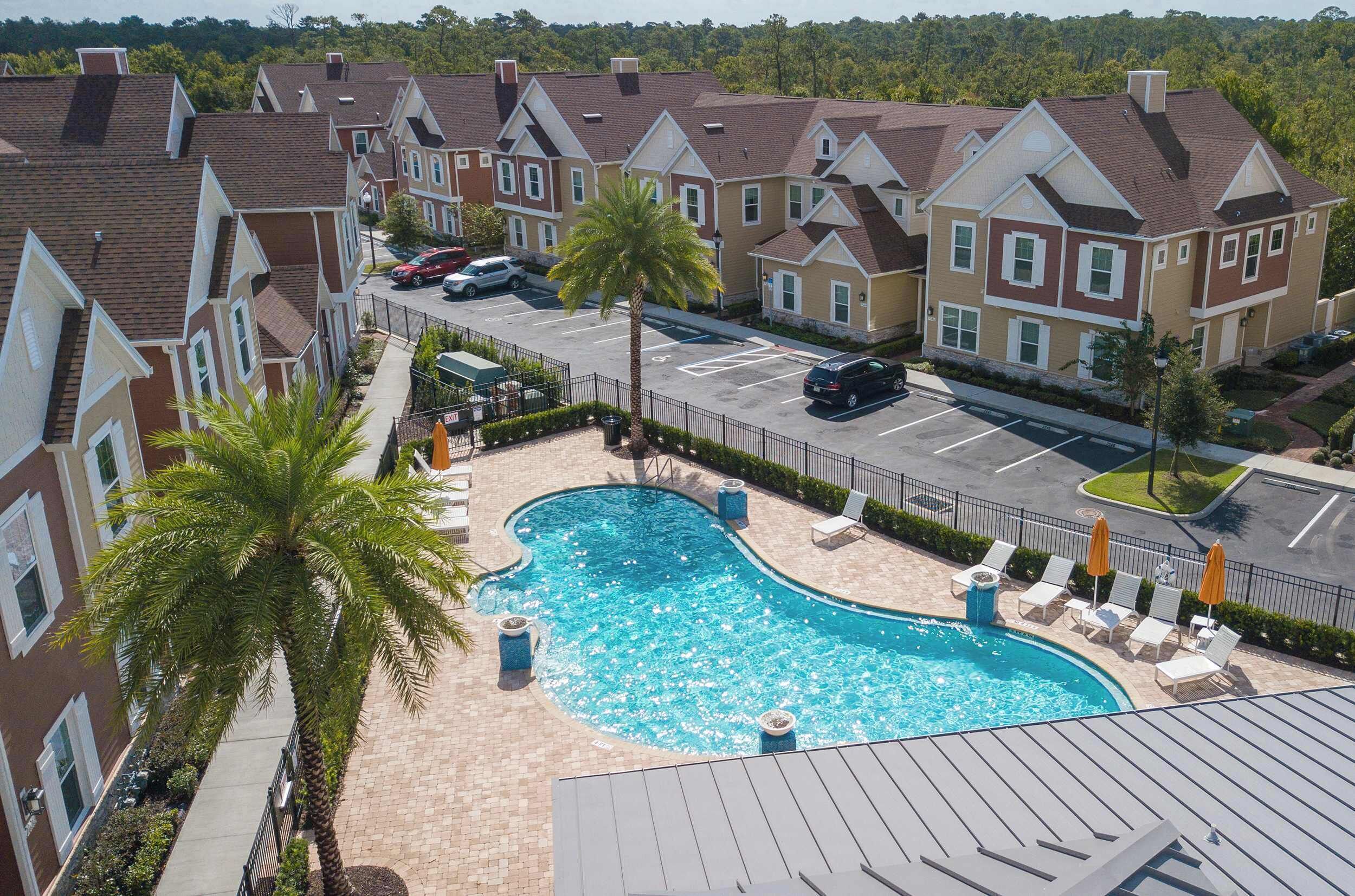 A residential building with a swimming pool, parking, and a palm tree.