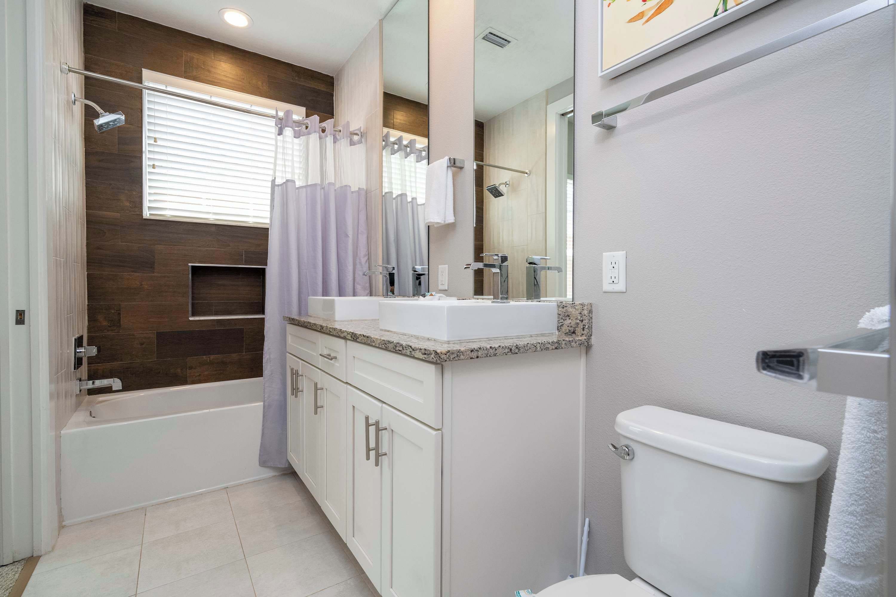 A modern bathroom with a bathtub, a shower, a toilet, and a vanity with a mirror.