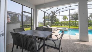 An outdoor patio with a table and chairs, a ceiling fan, and a view of a swimming pool. - Home 6bed , Themed Rooms, Game Room, Storey Lake (Kissimmee)