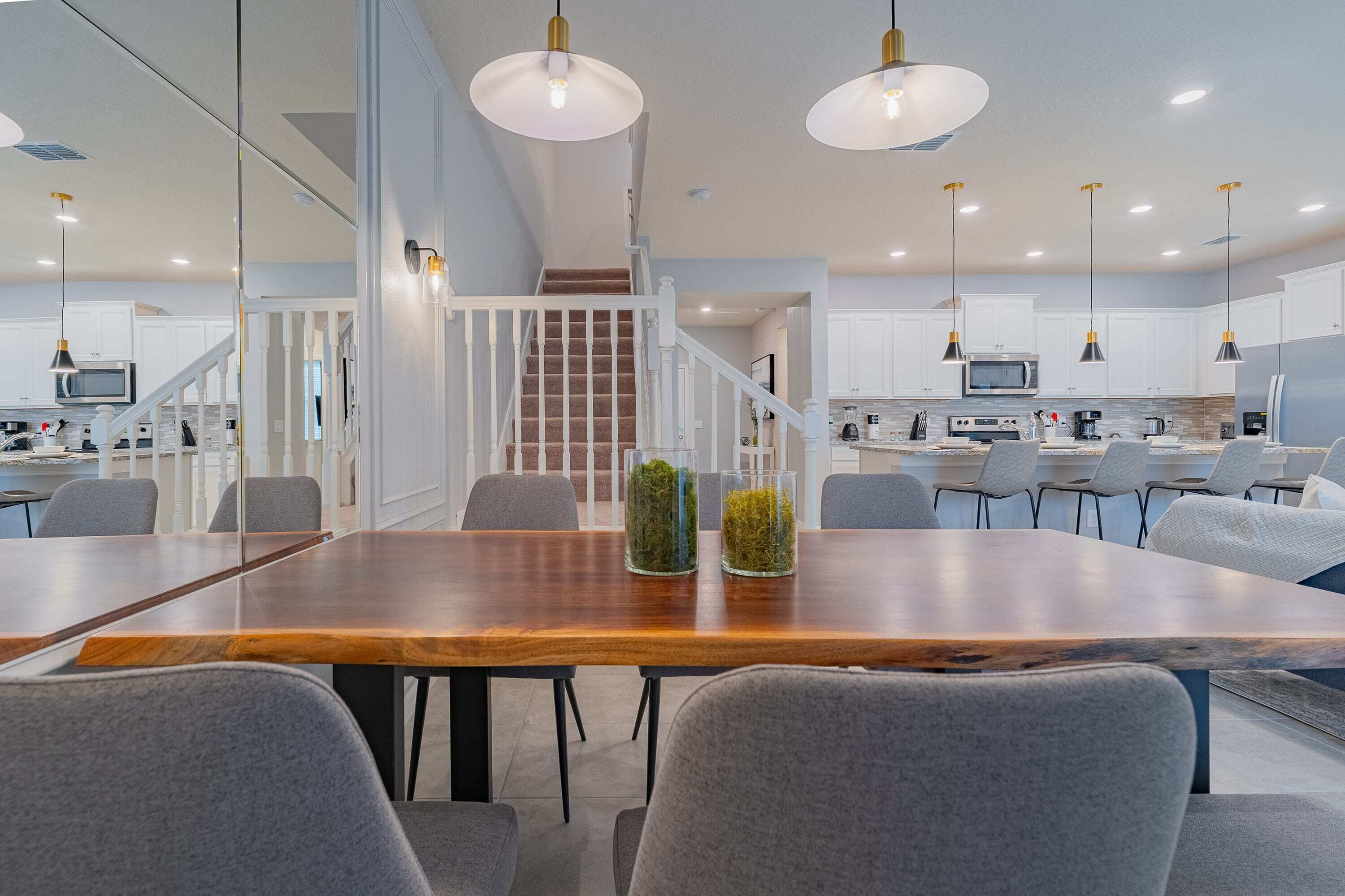 A modern dining area with a wooden table, grey chairs, and pendant lighting.
