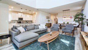 A spacious living area with a sectional sofa, a wooden coffee table, and a dining table with chairs. - Chic Home, Themed Bedrooms, Game Room, Best Spot (Kissimmee)