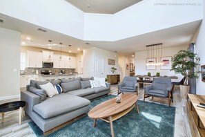 A spacious living area with a sectional sofa, a wooden coffee table, and a dining table with chairs. - Chic Home, Themed Bedrooms, Game Room, Best Spot (Kissimmee)