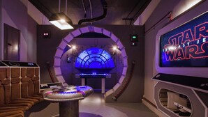 A Star Wars-themed room with a gaming console, a futuristic seating area, and a large screen displaying the movie title. - Chic Home, Themed Bedrooms, Game Room, Best Spot (Kissimmee)