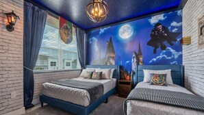 Un dormitorio con dos camas, una pared de ladrillo, una ventana con cortinas, un mural del cielo nocturno y una araña.