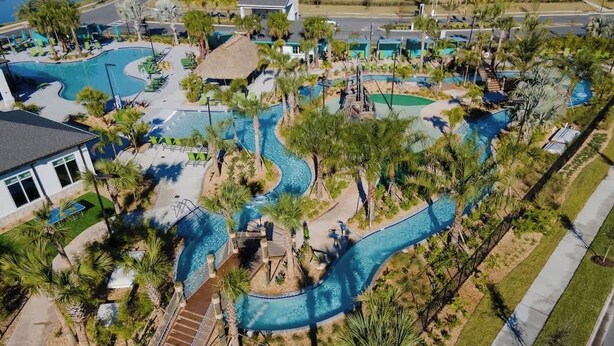 Oversigtsbillede af et resort med flere swimmingpools, palmer og en snoet vandrutsjebane.