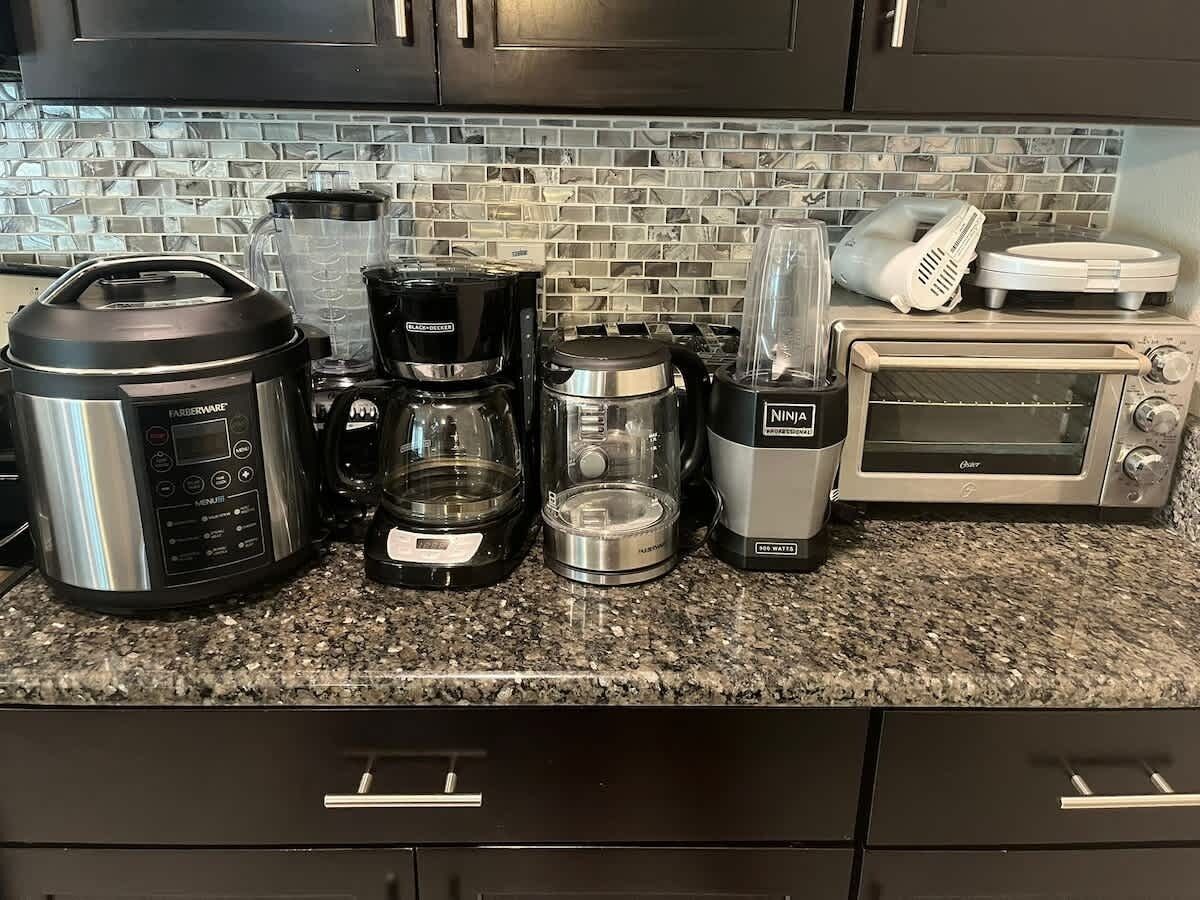 Eine Küche mit Granit Arbeitsplatte, einer Kaffeemaschine, einem Mixer, einem Toaster und einer Mikrowelle.