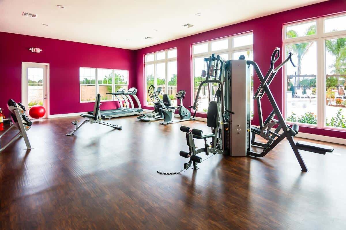 A gym with treadmills, weight machines, and a red wall.