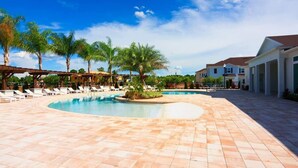 Ein Poolbereich mit Liegestühlen, Palmen und einer überdachten Terrasse.