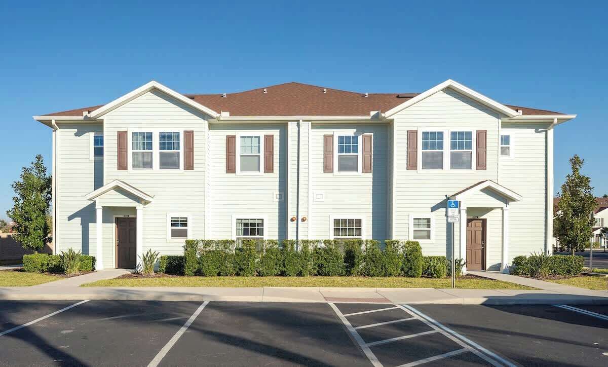 A two-story building with a symmetrical facade, featuring a central entrance flanked by windows and a small porch area.