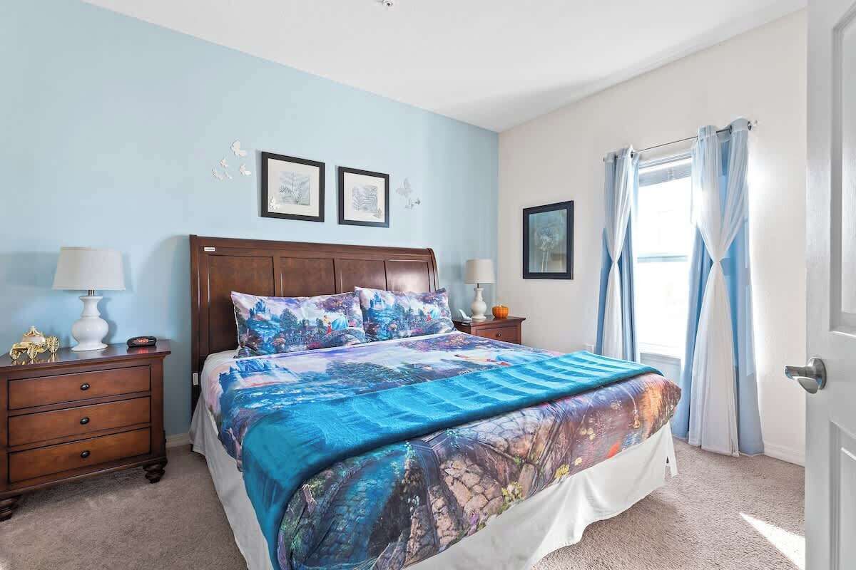 A bedroom with a large bed, two nightstands, a dresser, and a door with curtains.