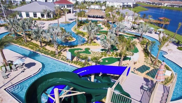 A water park with a large water slide, multiple pools, and surrounding palm trees. - Luxury Decor 6BR at Storey Lake Sleeps 16 (Kissimmee)