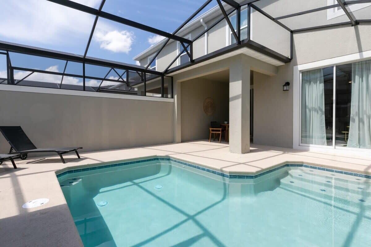 A swimming pool with a glass ceiling, a lounge chair, and a view of the sky.