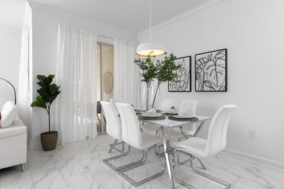 A dining area with a white table, chairs, and a hanging light fixture.