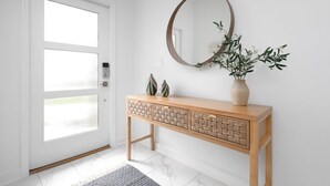 A minimalist entryway with a wooden console table, a round mirror, and a potted plant. - Chic Modern Home- Mickey & Star Wars Magic (Davenport)