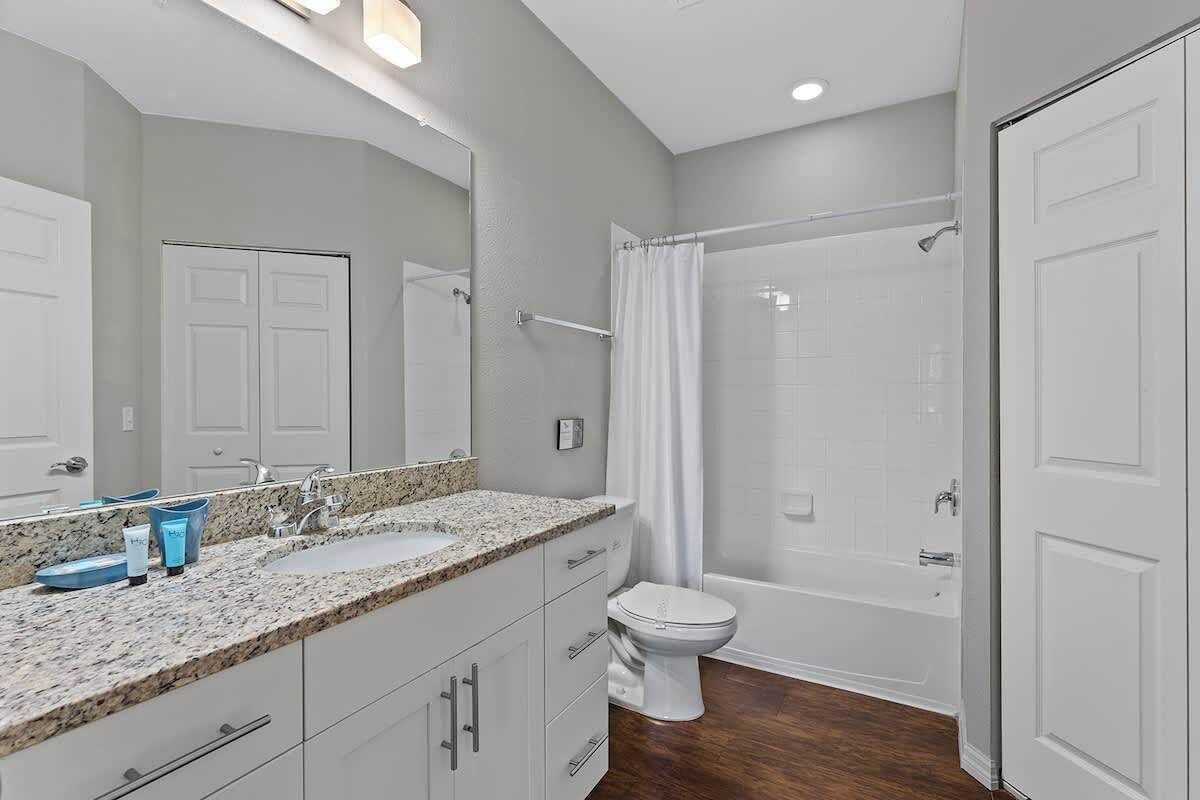 A bathroom with a double sink vanity, a toilet, a bathtub, and a shower.
