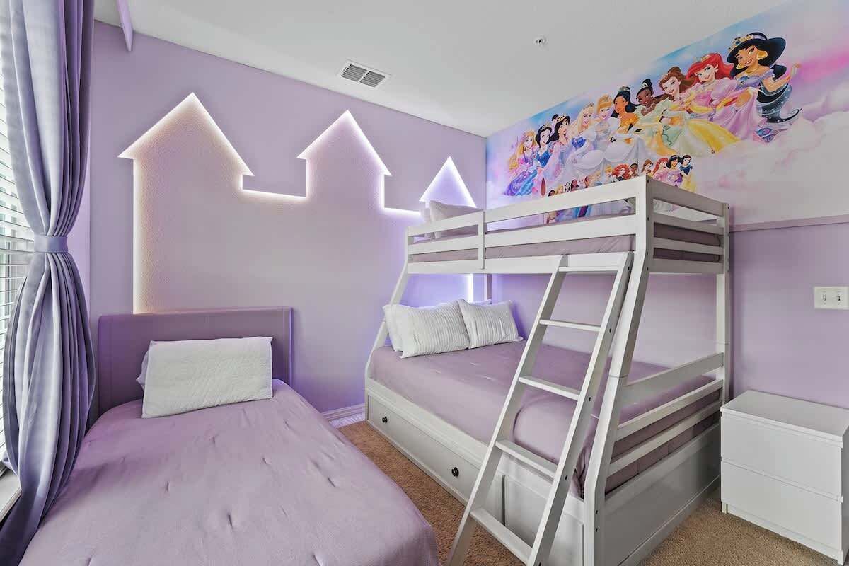 A room with a bunk bed, a single bed, a ladder, a white dresser, and a wall mural.