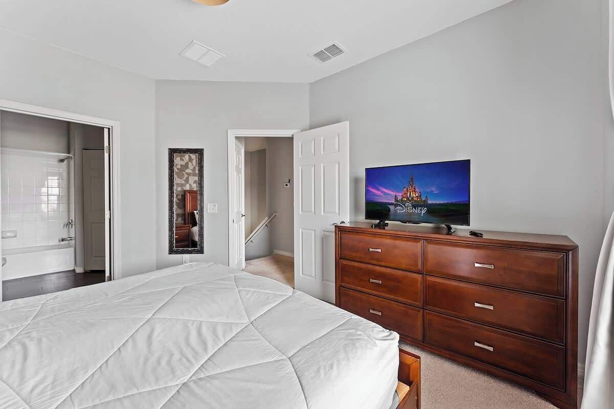 A bedroom with a bed, a dresser, a television, and a mirror.