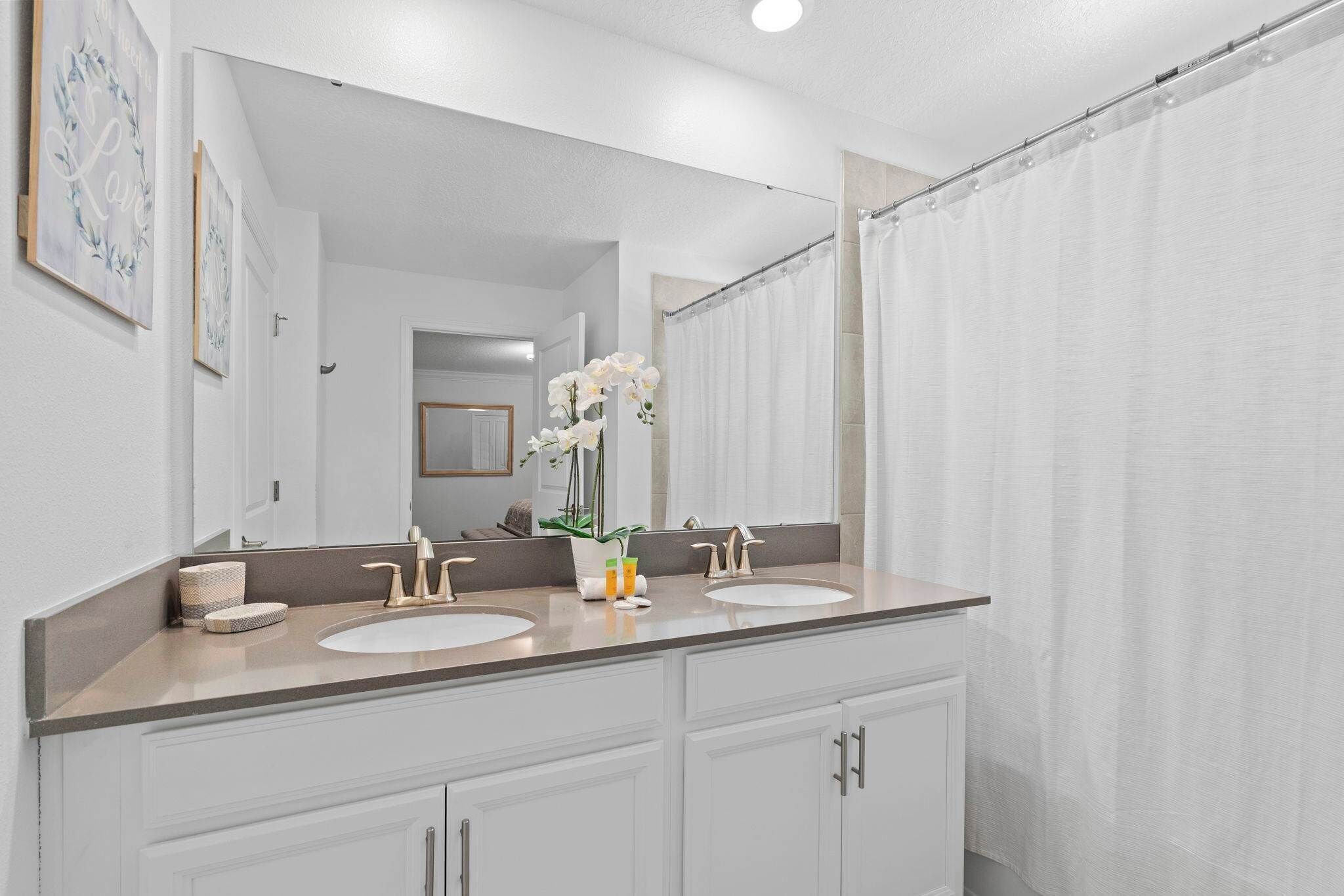 A bathroom with a double sink vanity, a large mirror, and a shower curtain.