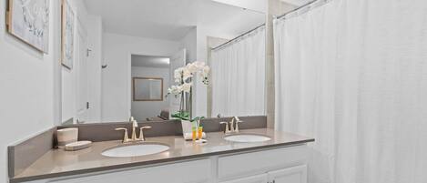 A bathroom with a double sink vanity, a large mirror, and a shower curtain.