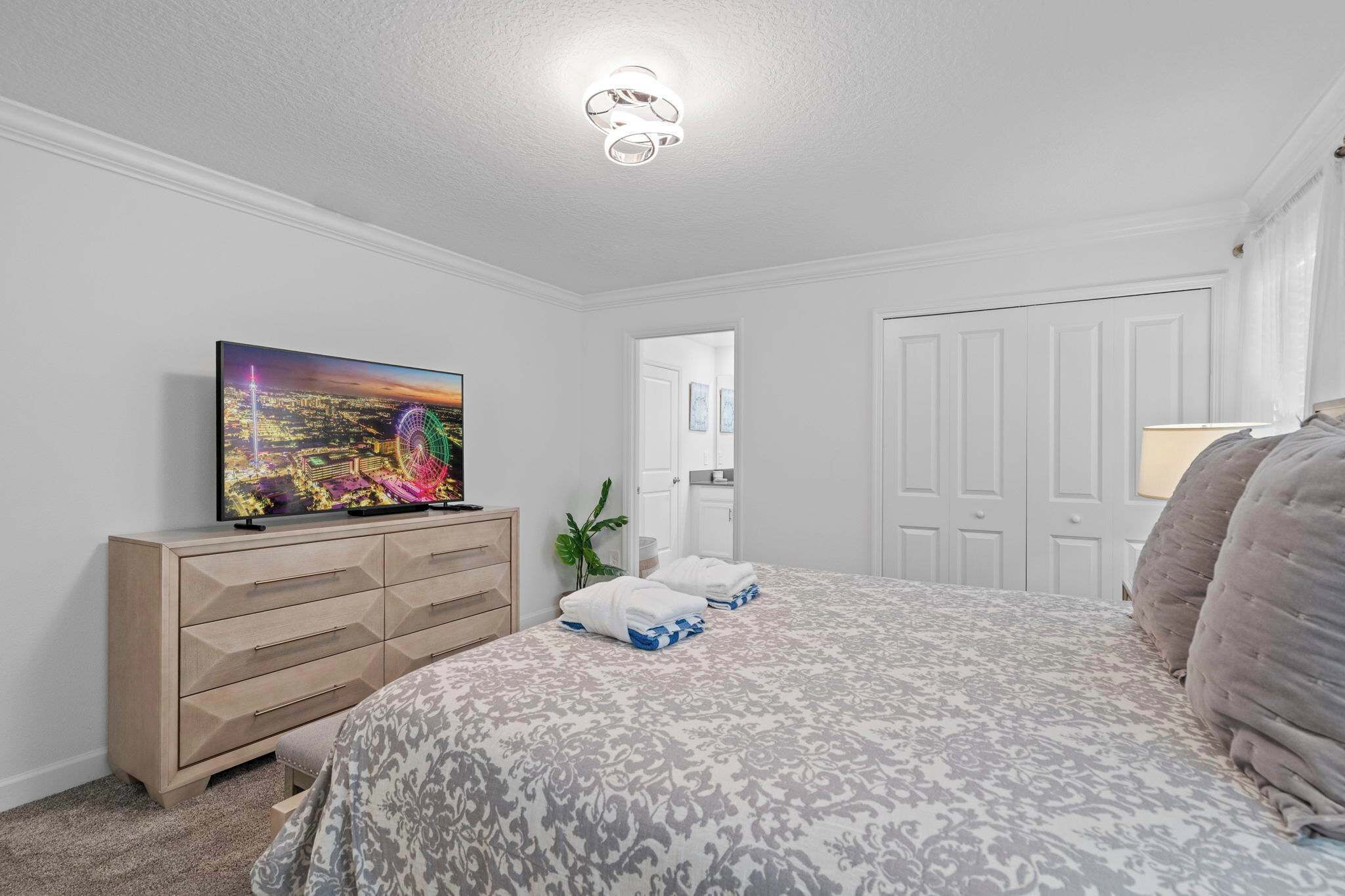Un dormitorio con cama, cómoda, televisor y puerta.