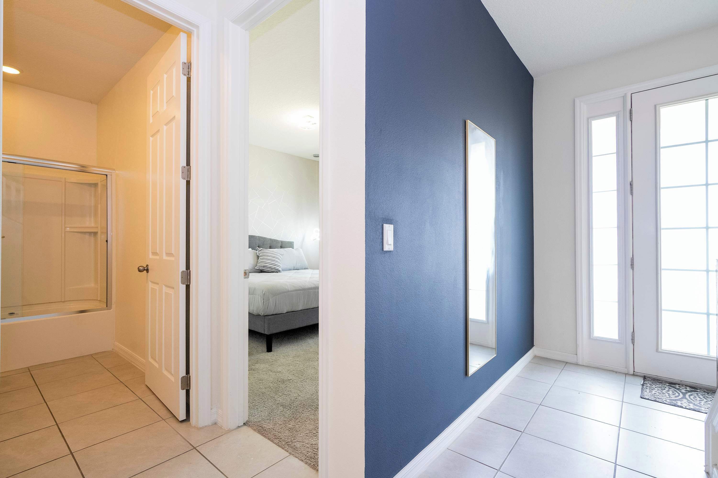 A hallway with a blue wall, white door, and a glass shower enclosure.