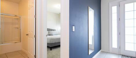 A hallway with a blue wall, white door, and a glass shower enclosure.