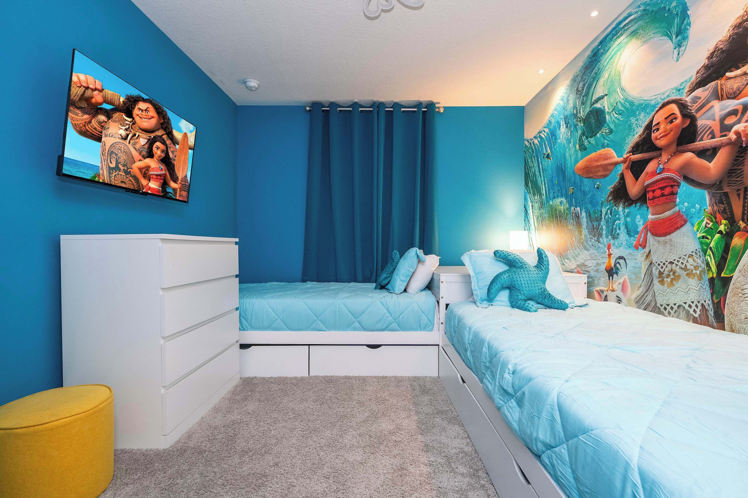 Un dormitorio con cama, cómoda, televisor montado en la pared y un mural.